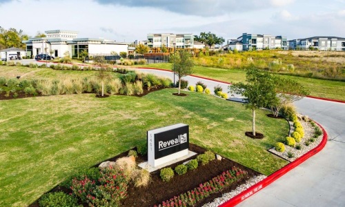 reveal 54 sign at property entrance surrounded by greenery