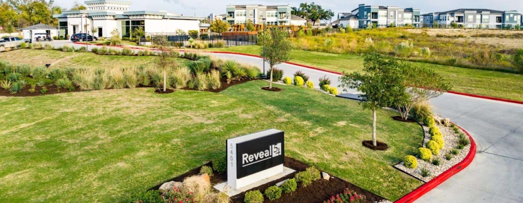 reveal 54 sign at property entrance surrounded by greenery