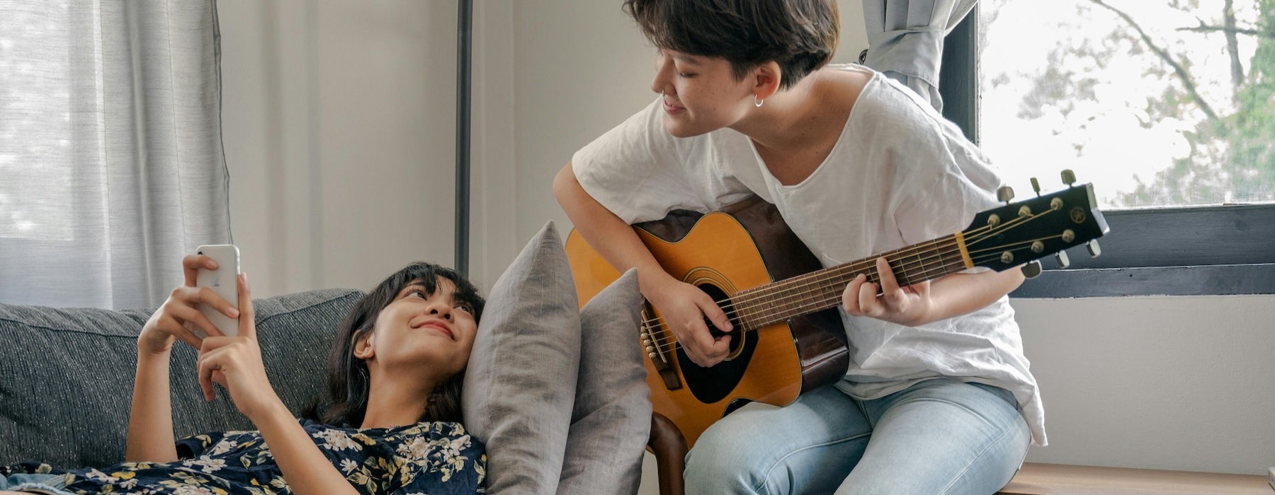a person playing the guitar and a person laying on a couch