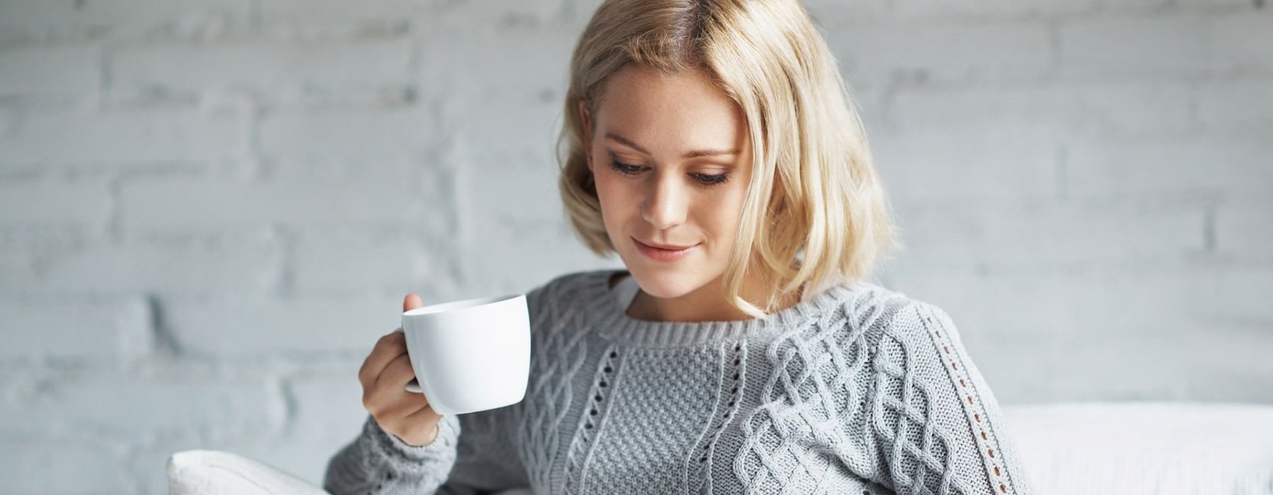 Woman sitting in a living room drinking coffee