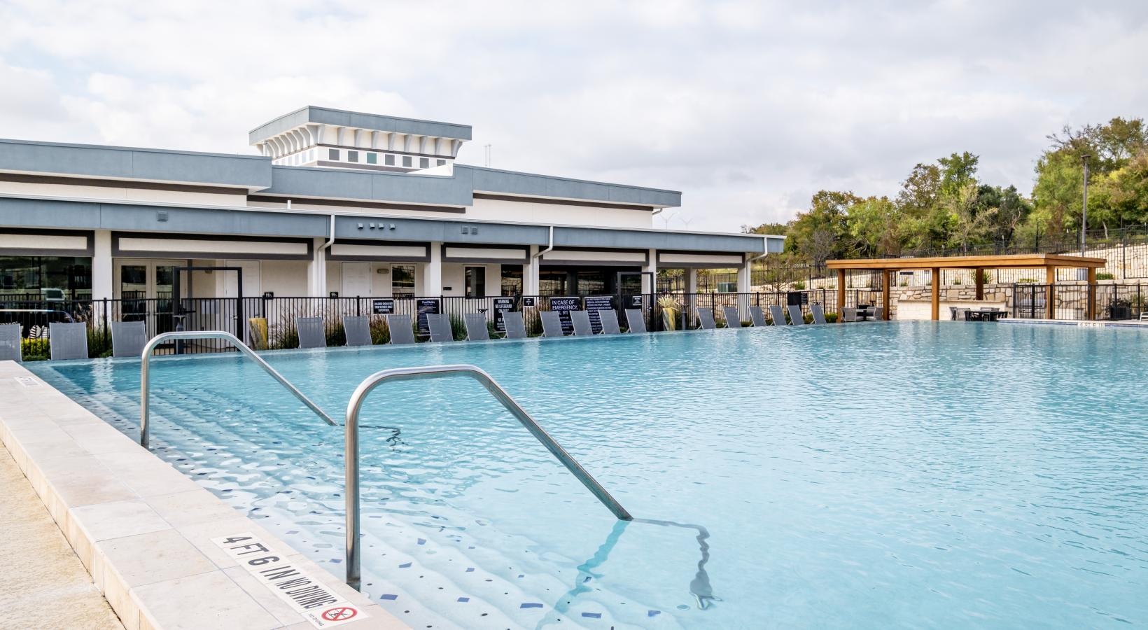 Relax and unwind poolside a pool with a building in the background